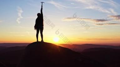 一个女人<strong>站在山顶</strong>上高兴地挥手拿着冰斧的照片.